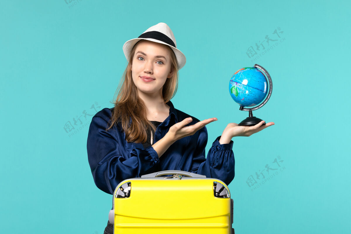 地球仪正面图年轻女子手持地球仪 准备在蓝色桌面飞机上度假女性度假之旅远航大海女性人女士