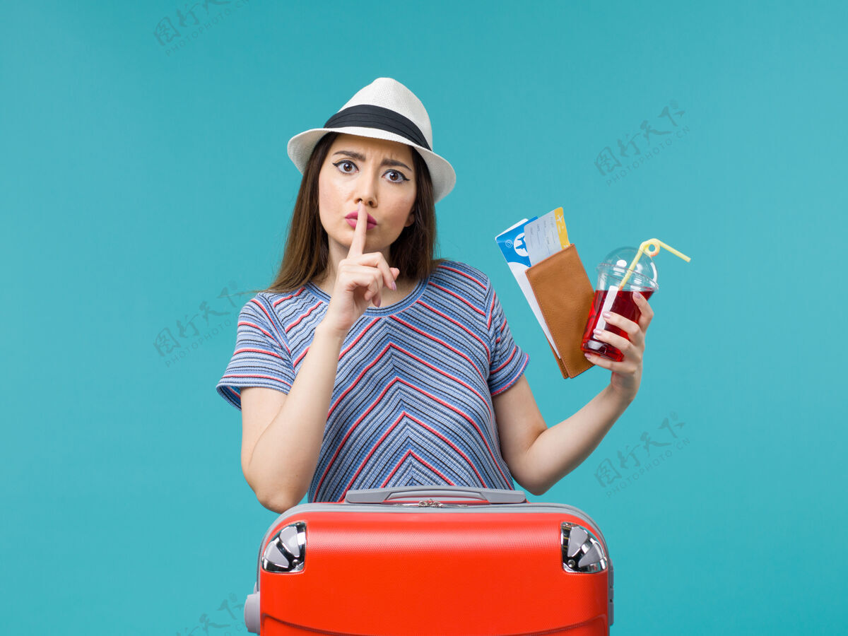 票前景度假中的女人拿着果汁拿着蓝色背景上的机票旅行女海飞机夏天成人微笑果汁