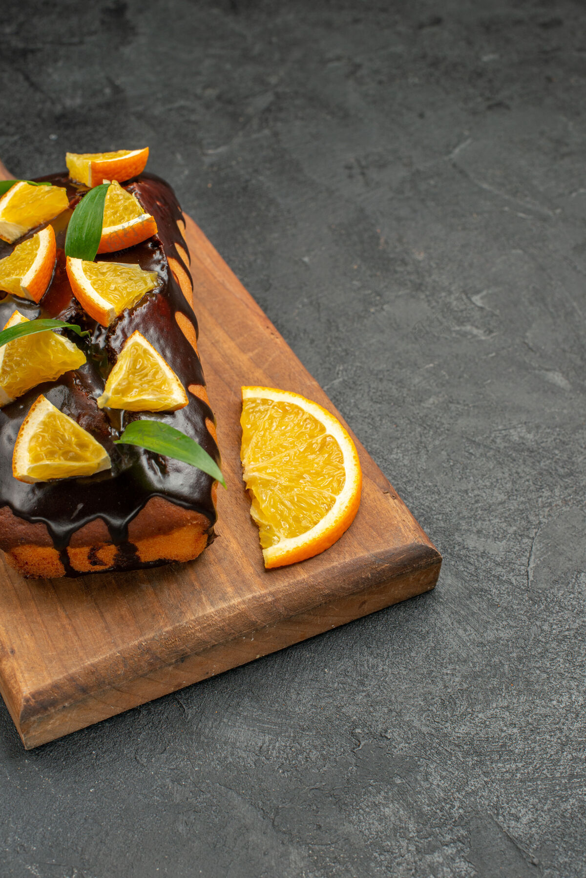 餐桌黑色桌子上的砧板上装饰着柠檬和巧克力的美味蛋糕的垂直视图切新鲜饮食