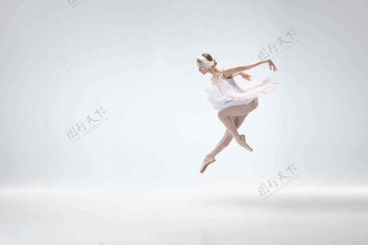 移动以白色工作室为背景的年轻优雅的芭蕾舞演员经典天鹅舞蹈