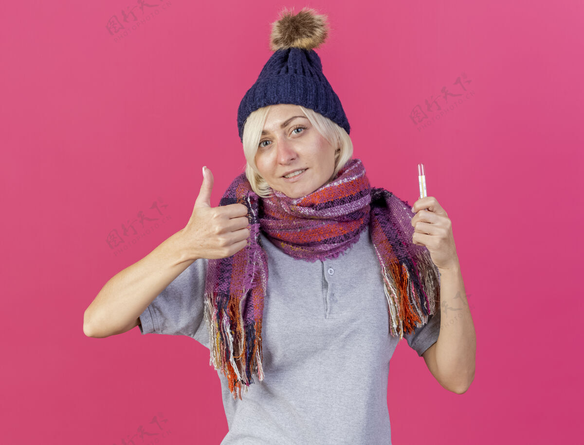 拇指高兴的年轻金发病斯拉夫妇女戴冬季帽子和围巾大拇指拜托年轻人帽子