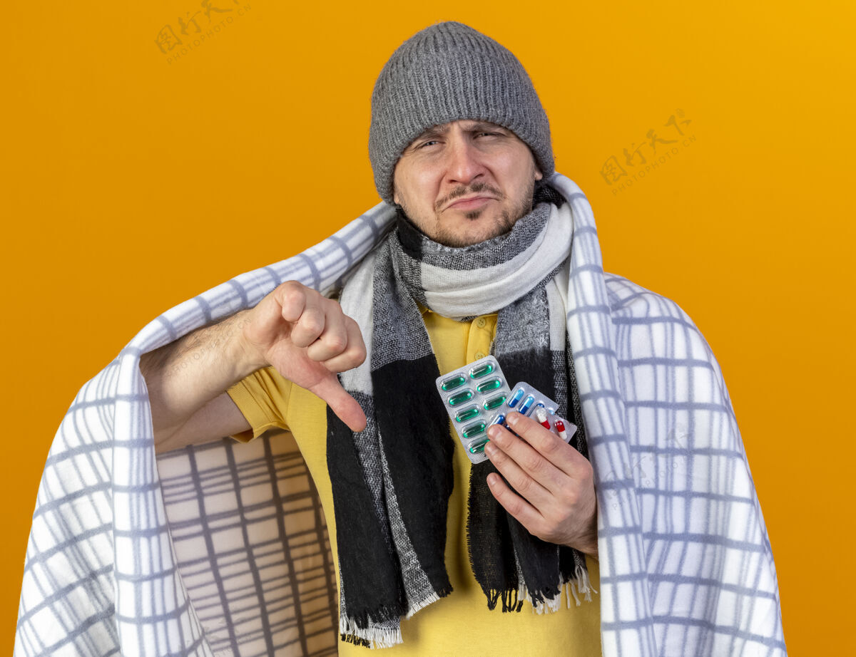 疾病年轻的金发病斯拉夫男子戴冬季帽子和围巾帽子不愉快拇指