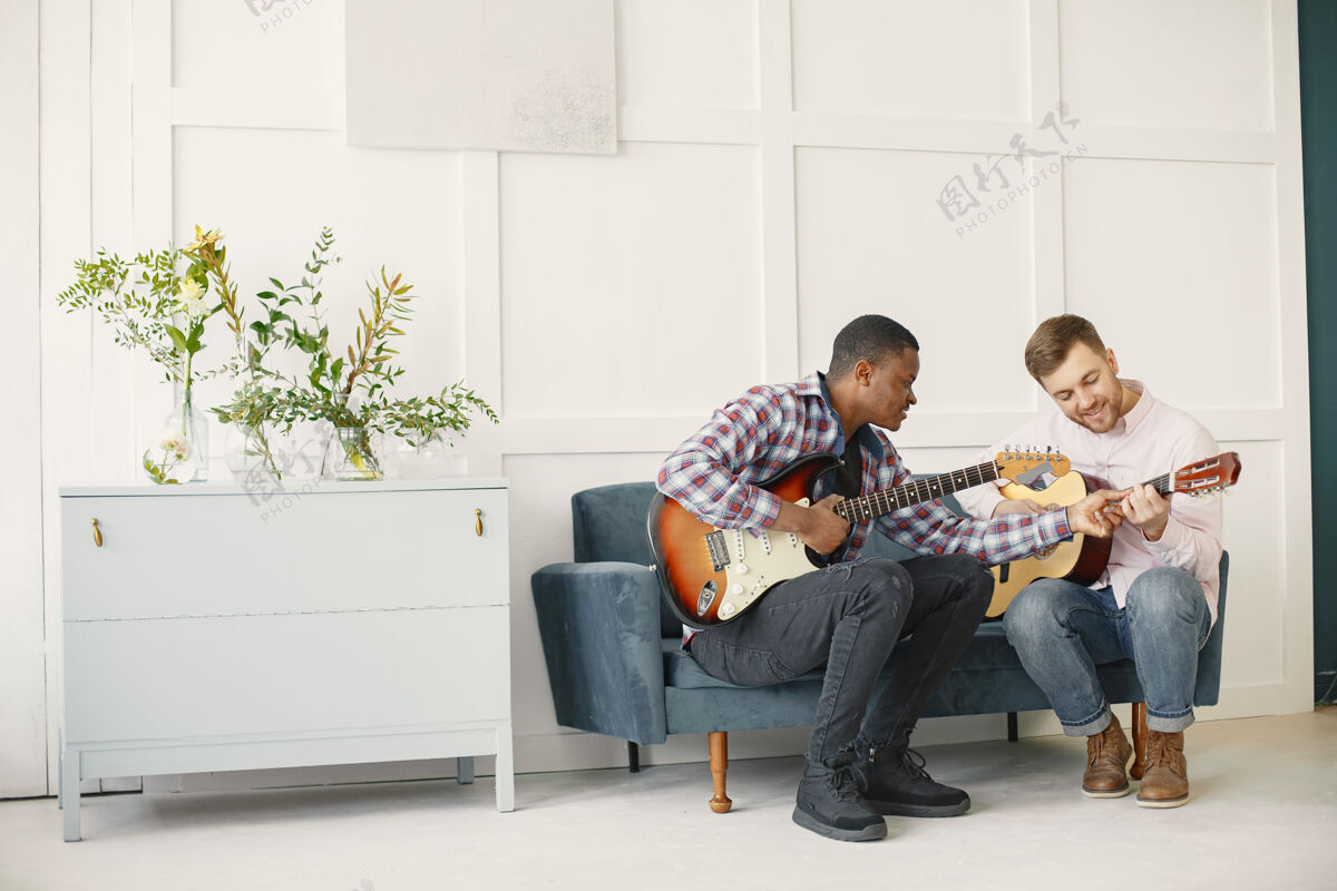 乐趣男人弹吉他 写音乐 非洲和高加索男人休闲成人旋律
