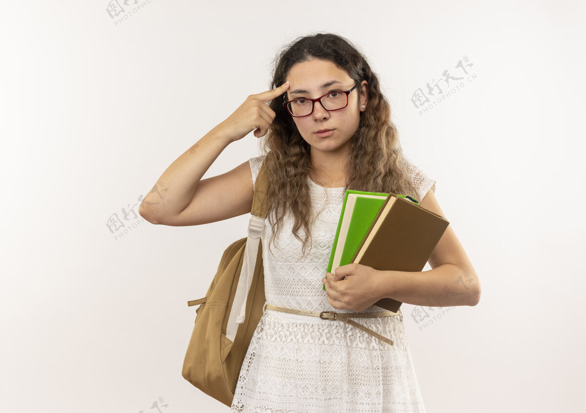 抱体贴的年轻漂亮的女学生戴着眼镜 背着书包 手指放在头上 看着隔离在白色墙上的前面人包漂亮