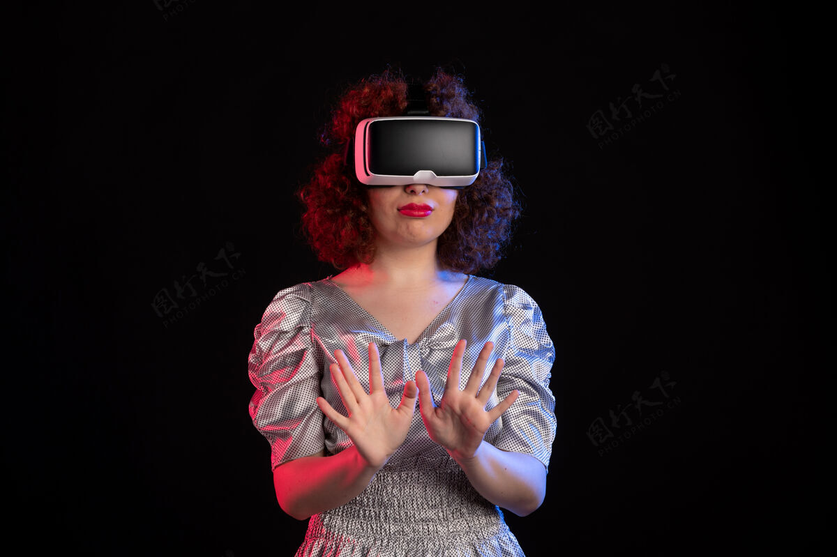肖像年轻女性戴着虚拟现实耳机在黑暗的表面视觉视觉女人
