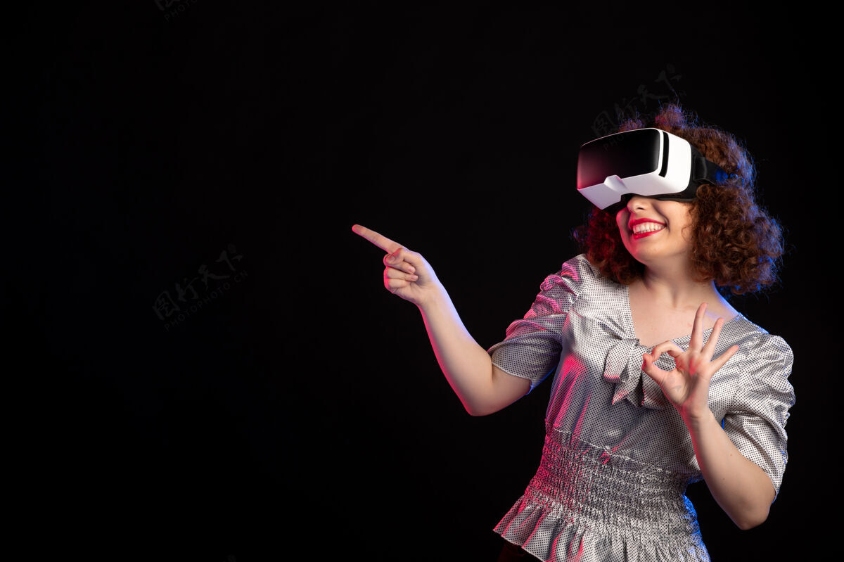 女人年轻女性戴着虚拟现实耳机在黑暗的表面姿势游戏视觉