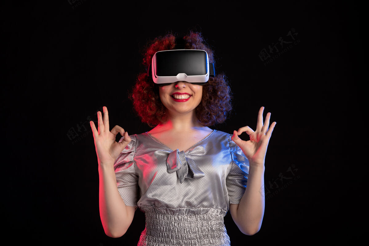 人美丽的女性戴着虚拟现实耳机在黑暗的表面视觉姿势女人