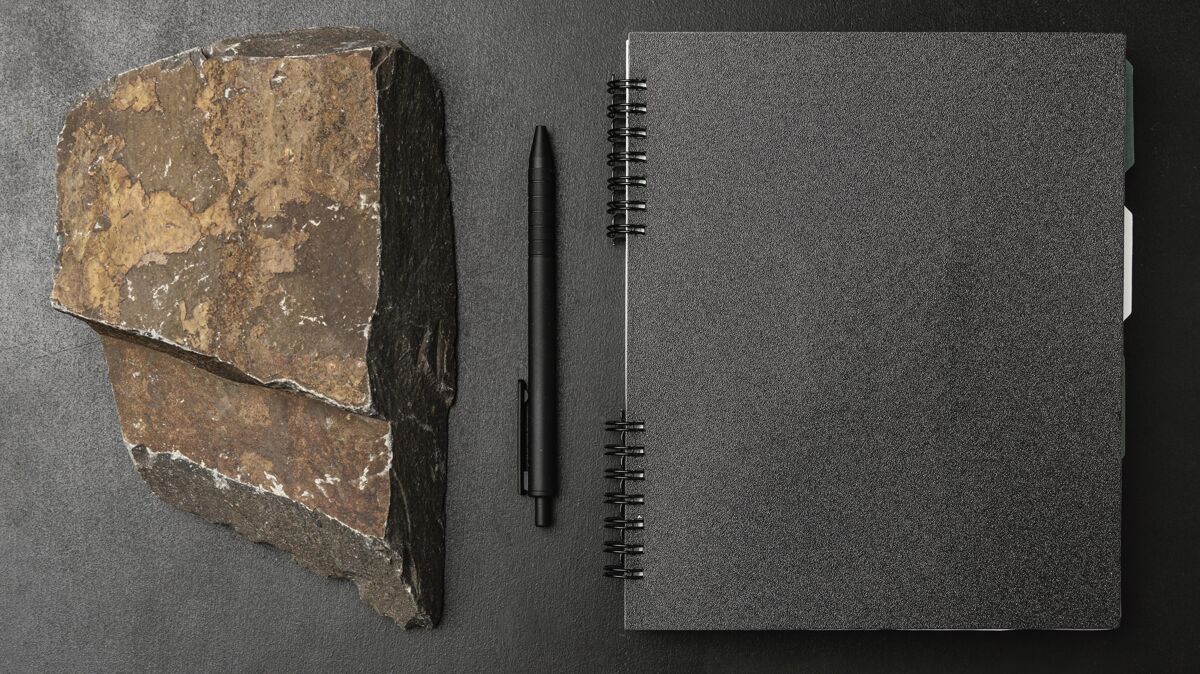 石头文具模型在黑暗的混凝土与崎岖的岩石笔记本水平纸