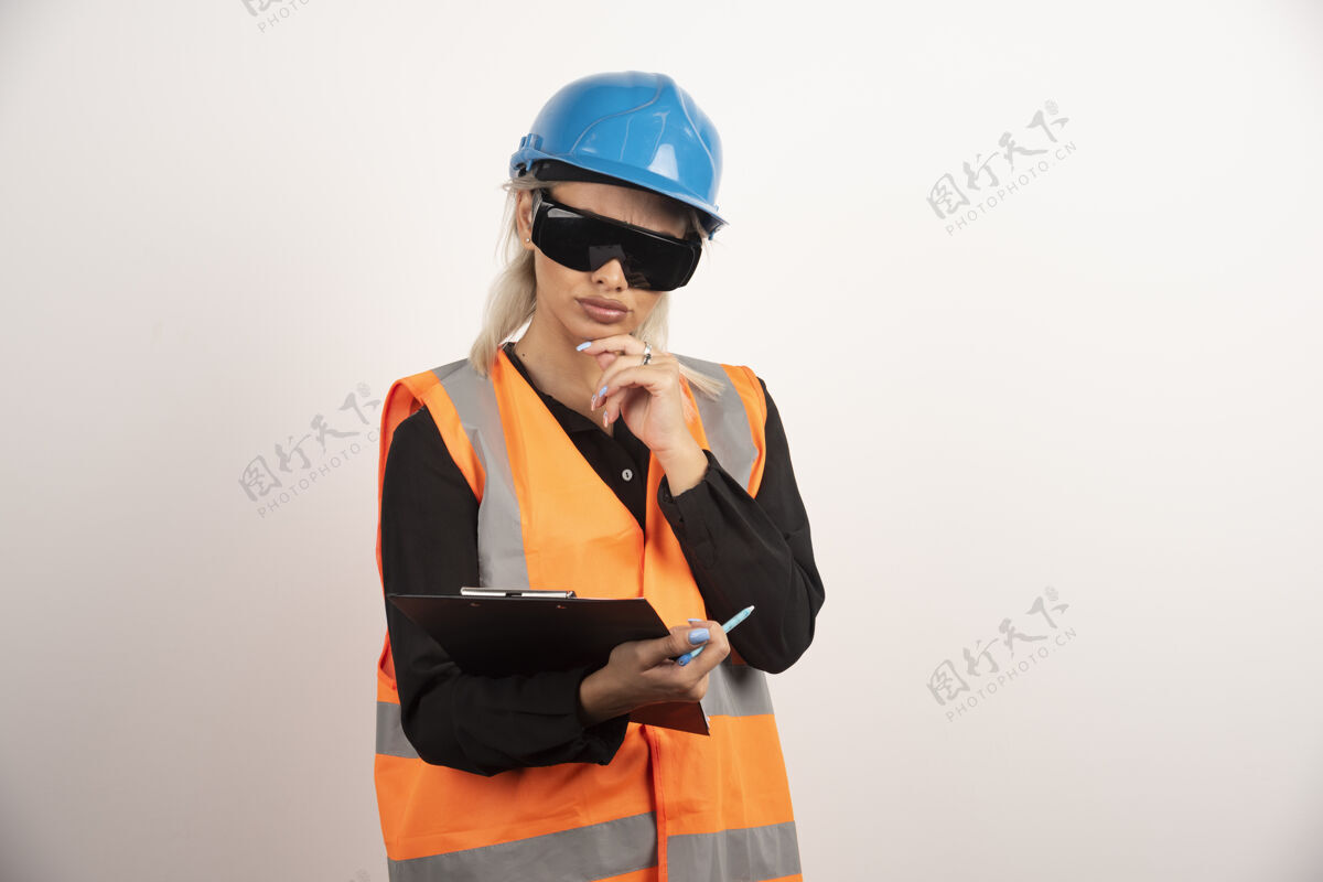 剪贴板戴眼镜的女工程师看着白色背景上的剪贴板高质量的照片眼镜女背心