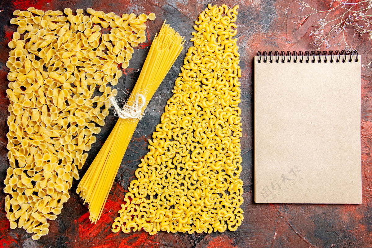 笔记本未煮熟的意大利面作为一种形式的通心粉曼尼科蒂和黑色背景上的笔记本俯视图玉米生面食有机