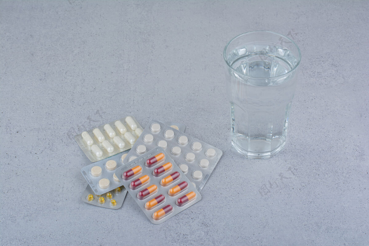 片剂各种包装的胶囊和药丸 还有一杯水药物药丸胶囊