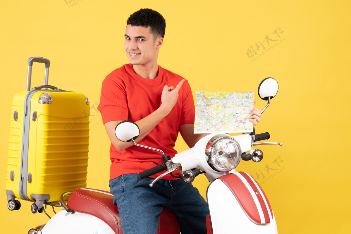 满意的年轻人正面图满意的年轻人穿着休闲服手持轻便摩托车旅游地图旅行人摩托车