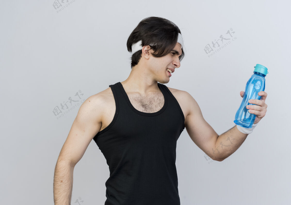 运动装一个穿着运动服 戴着头巾 手里拿着一瓶水的年轻人站在白色的墙上 看着它困惑的样子运动姿势头带