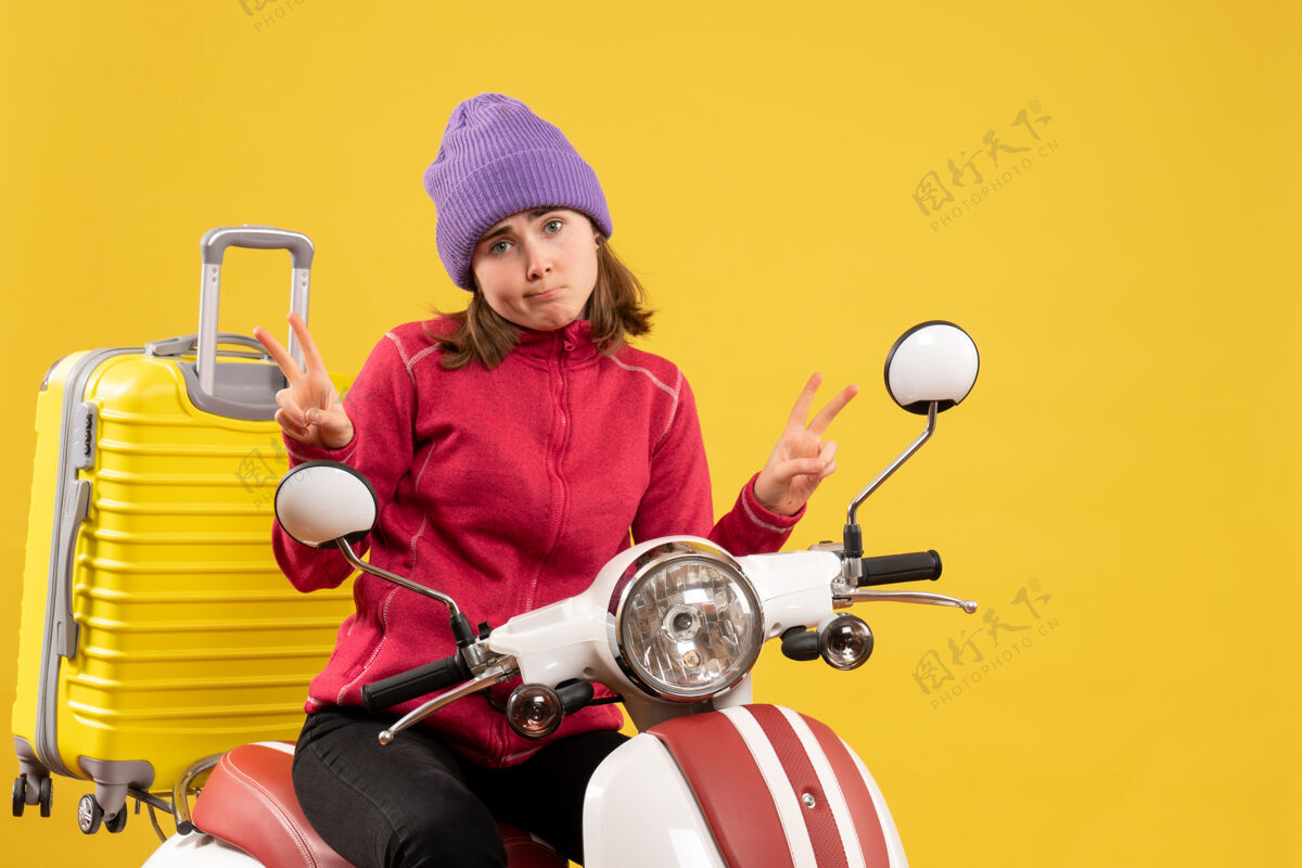 制造前视图：骑着轻便摩托车的年轻女子在做胜利手势前面摩托车摩托车