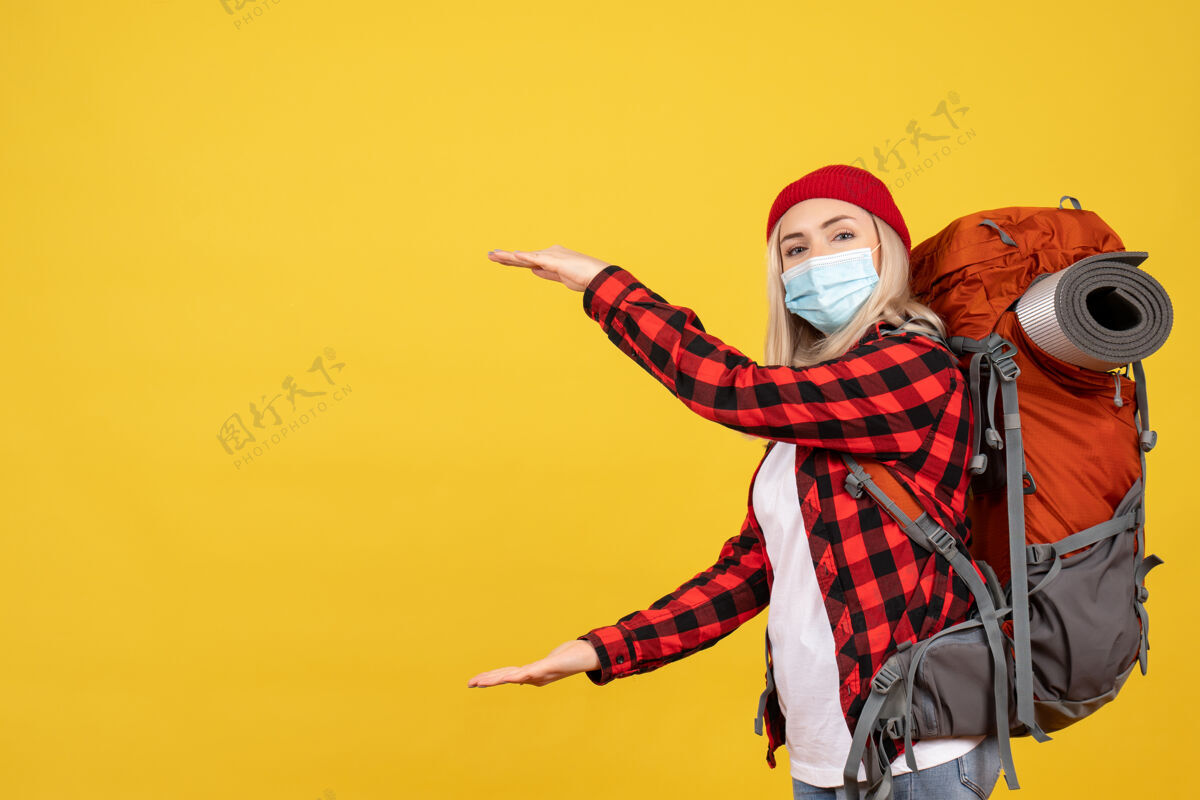 行动正面图：年轻的旅行者背着她的背包 双手放在黄色的墙上背包时尚前面