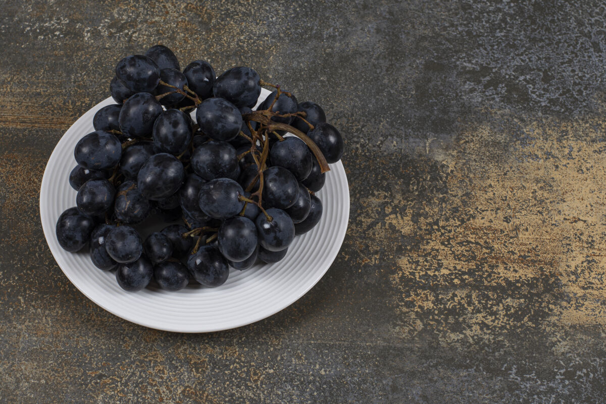 新鲜白色盘子上的一簇黑葡萄葡萄食品水果