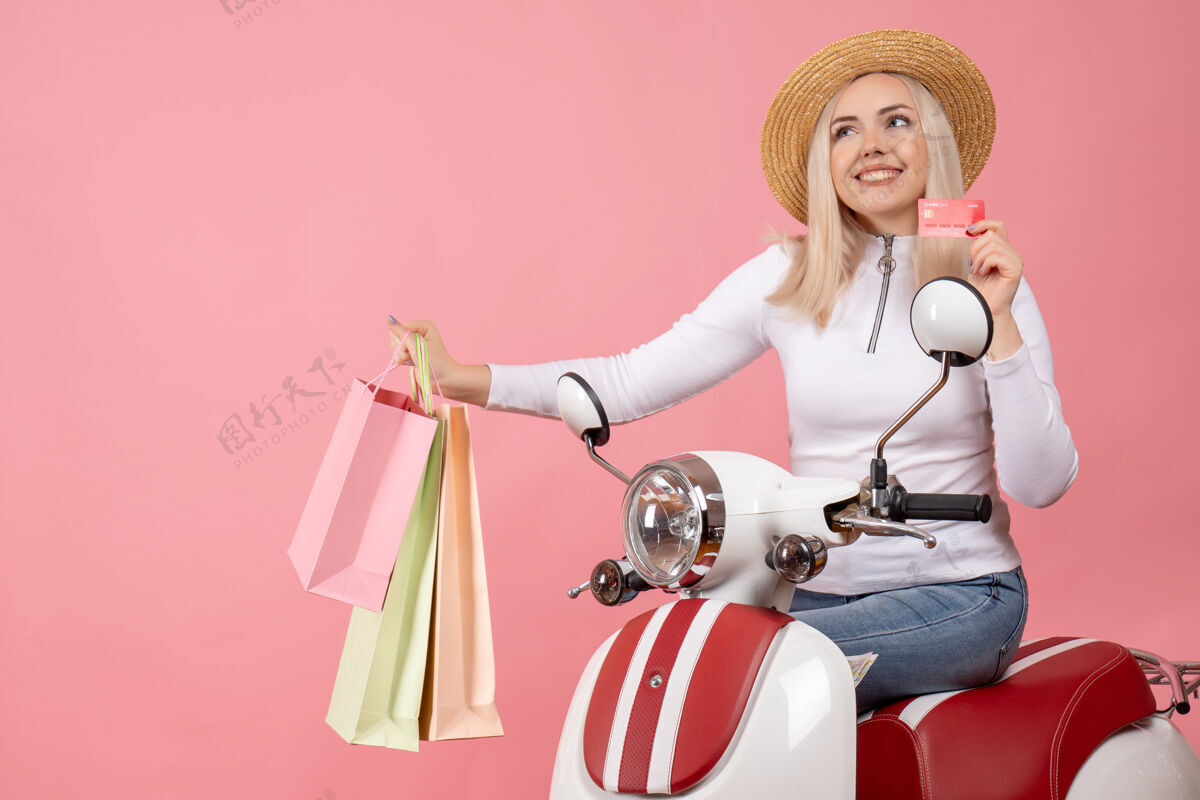 摩托车前视图骑着轻便摩托车的年轻女士举着购物袋和购物卡前面成人车辆