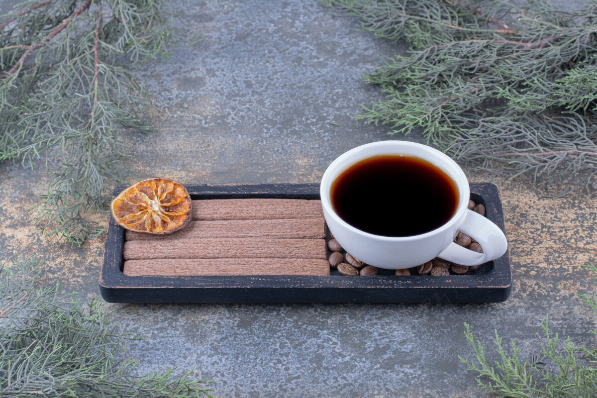 切片一杯浓咖啡 把饼干和咖啡豆放在黑盘子里热的杯子饼干