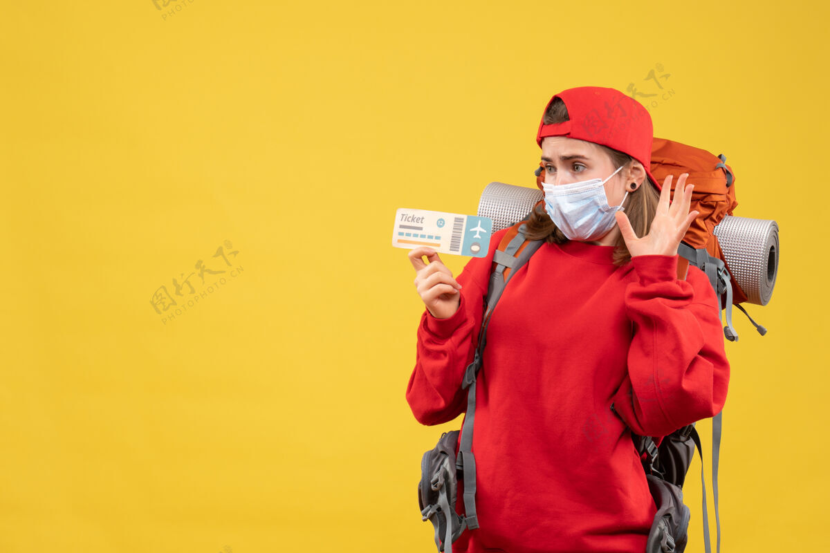 工作前视图困惑的女旅客背着背包和口罩拿着机票面具拿着前面