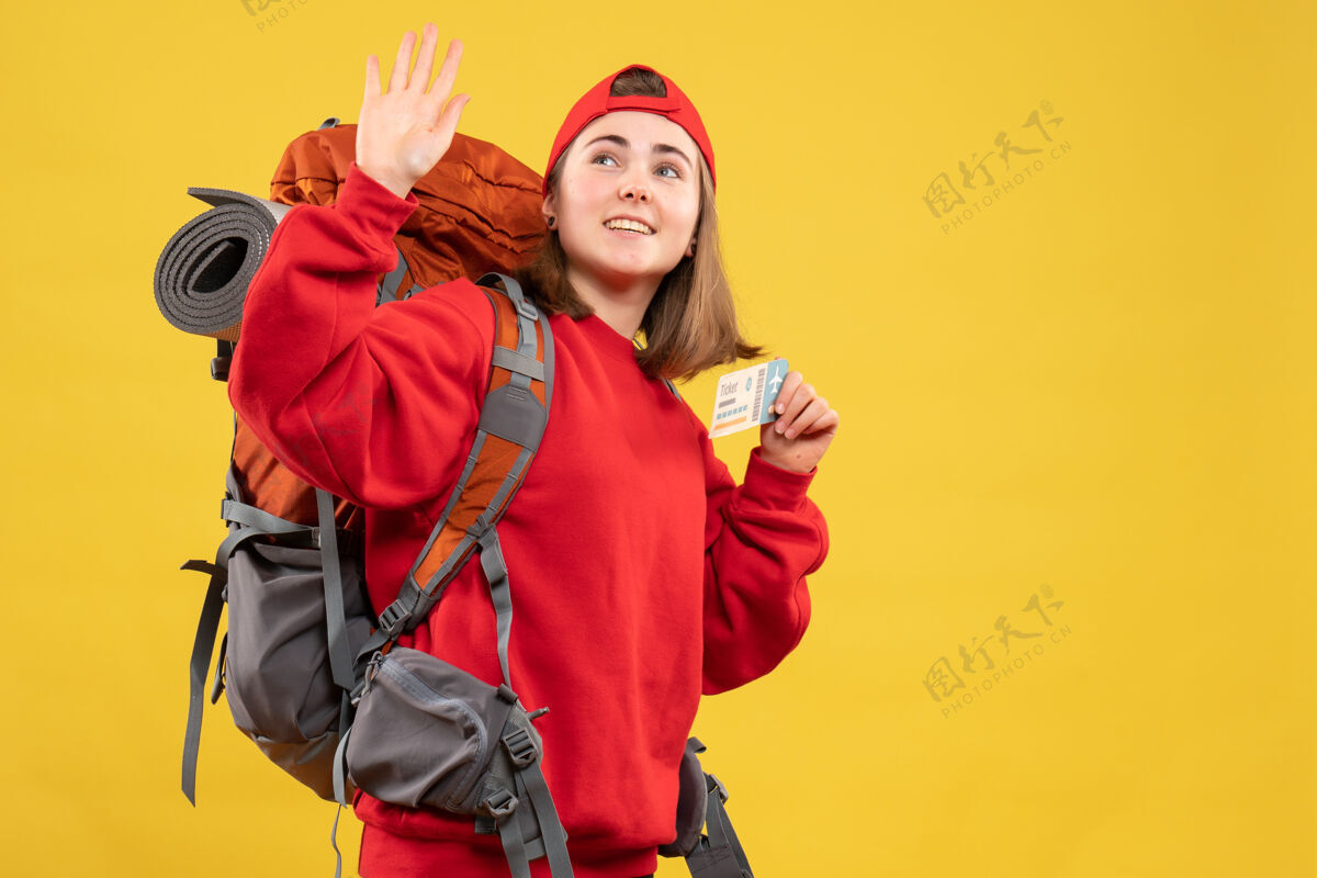 成人正面图漂亮的女徒步旅行者背着背包拿着机票挥手背包前面门票