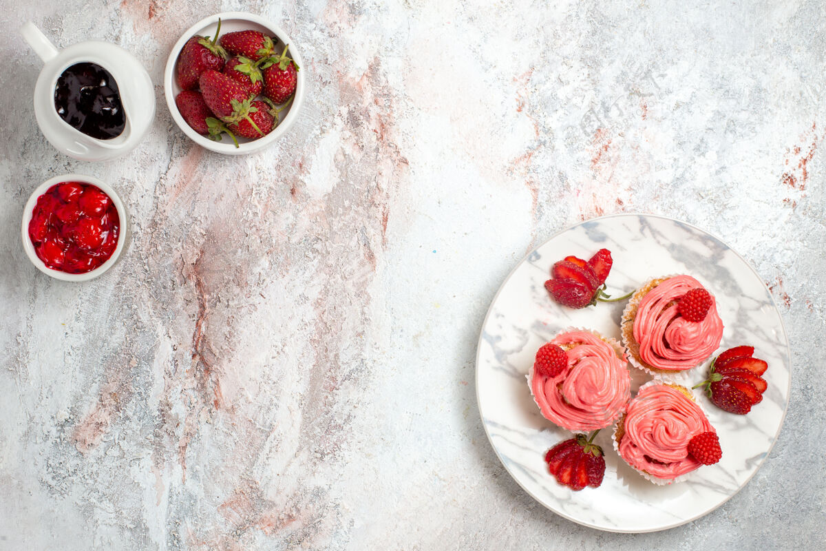饼干白色表面有果酱和巧克力棒的粉色草莓蛋糕俯视图鲜花棒茶