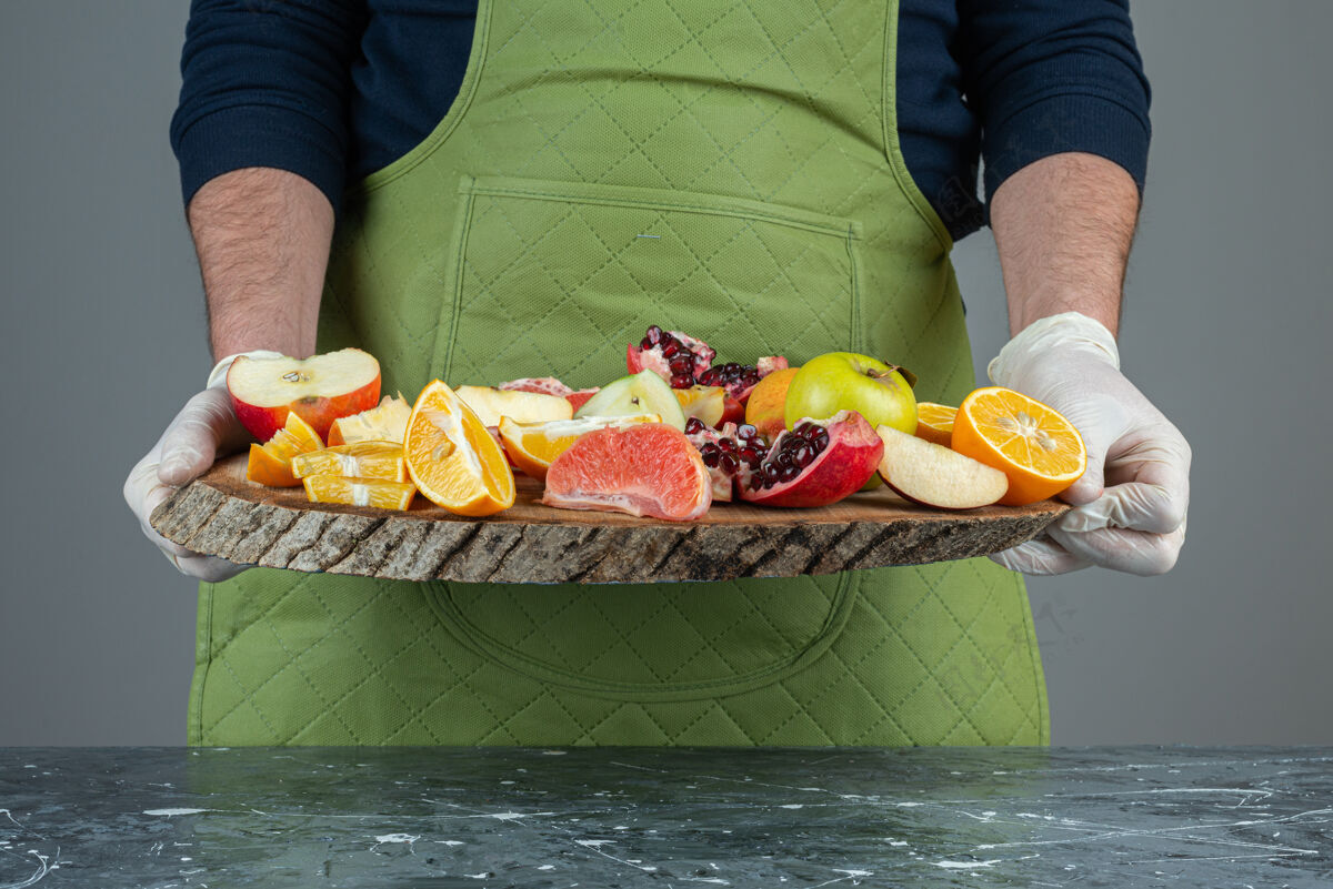 混合男性手拿一束新鲜水果放在大理石桌上烹饪刀切