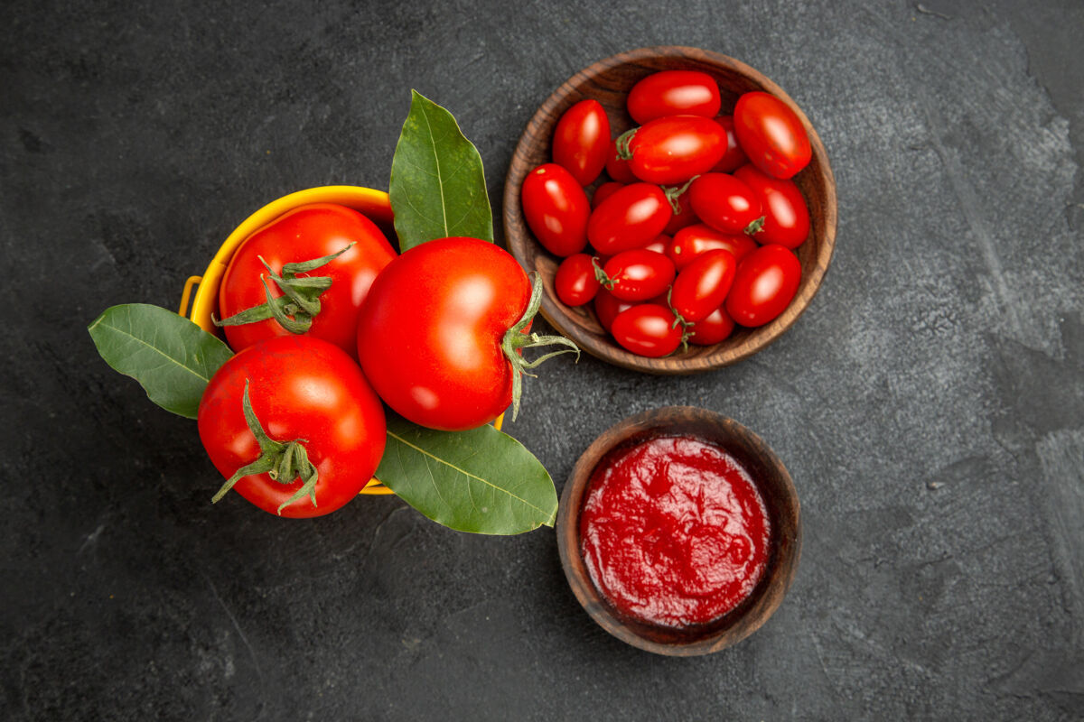 番茄顶视图一桶西红柿碗樱桃西红柿和番茄酱在黑暗的地面空间健康成熟蔬菜
