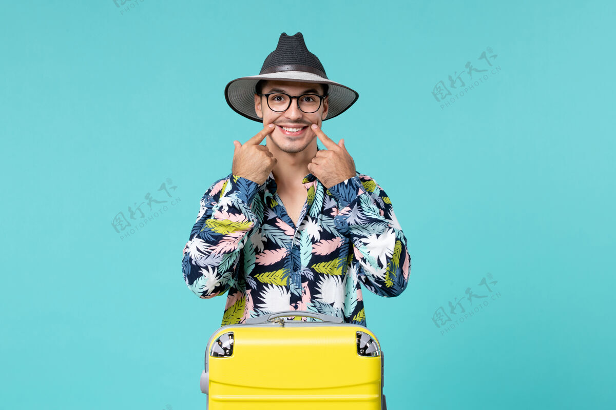 人年轻男子正拿着他的黄色袋子准备在蓝色的墙上旅行准备旅行旅行