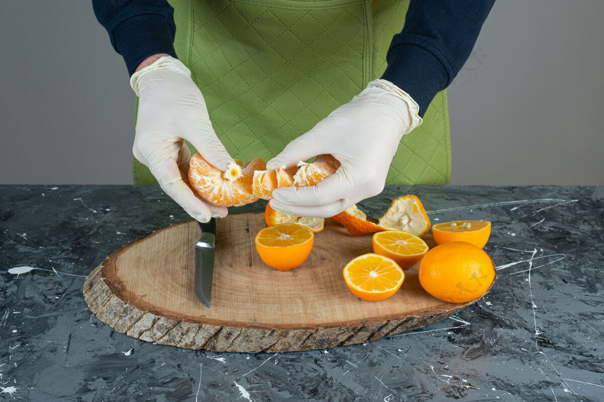 手男人的手拿着多汁的橘子放在大理石桌上准备烹饪水果