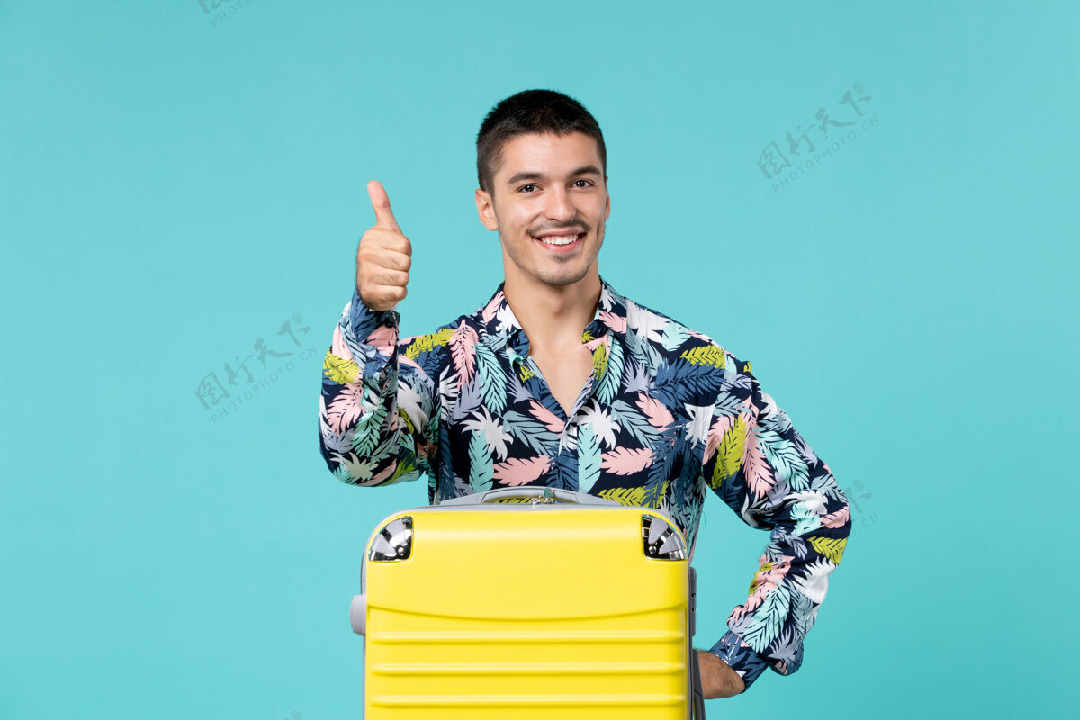 旅行年轻男子正准备旅行 黄色的包在蓝色的墙上微笑着旅行微笑前面