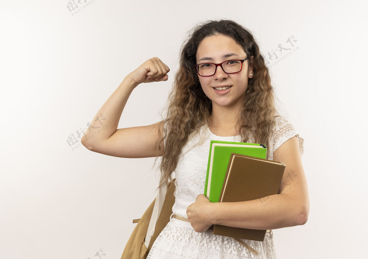 穿高兴的年轻漂亮的女学生戴着眼镜 背着书包 在白色的墙上做着强烈的孤立的手势衣服市民抱
