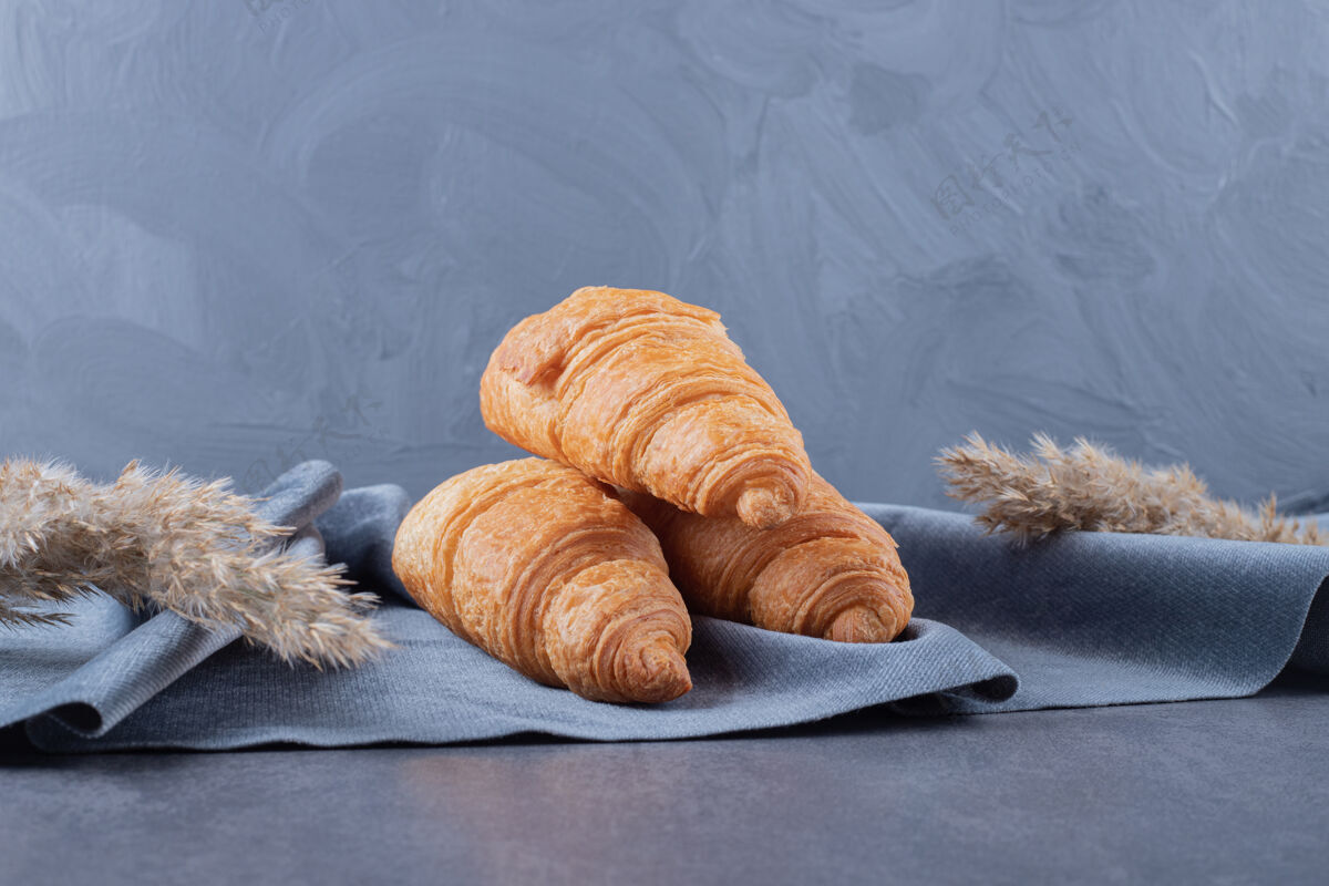 桌布三个新鲜的法式羊角面包放在灰色的棉餐巾上处理食谱面包