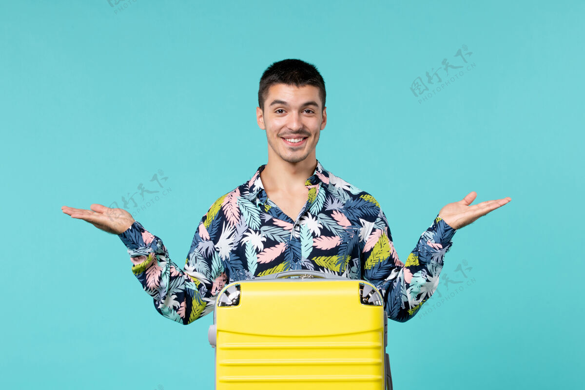 消费品年轻的男性正准备旅行 他的黄色袋子放在蓝色的墙上人年轻男性旅行