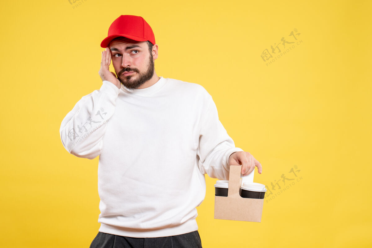 人黄色墙壁上的男快递员拿着送咖啡的正面图咖啡男信使工作