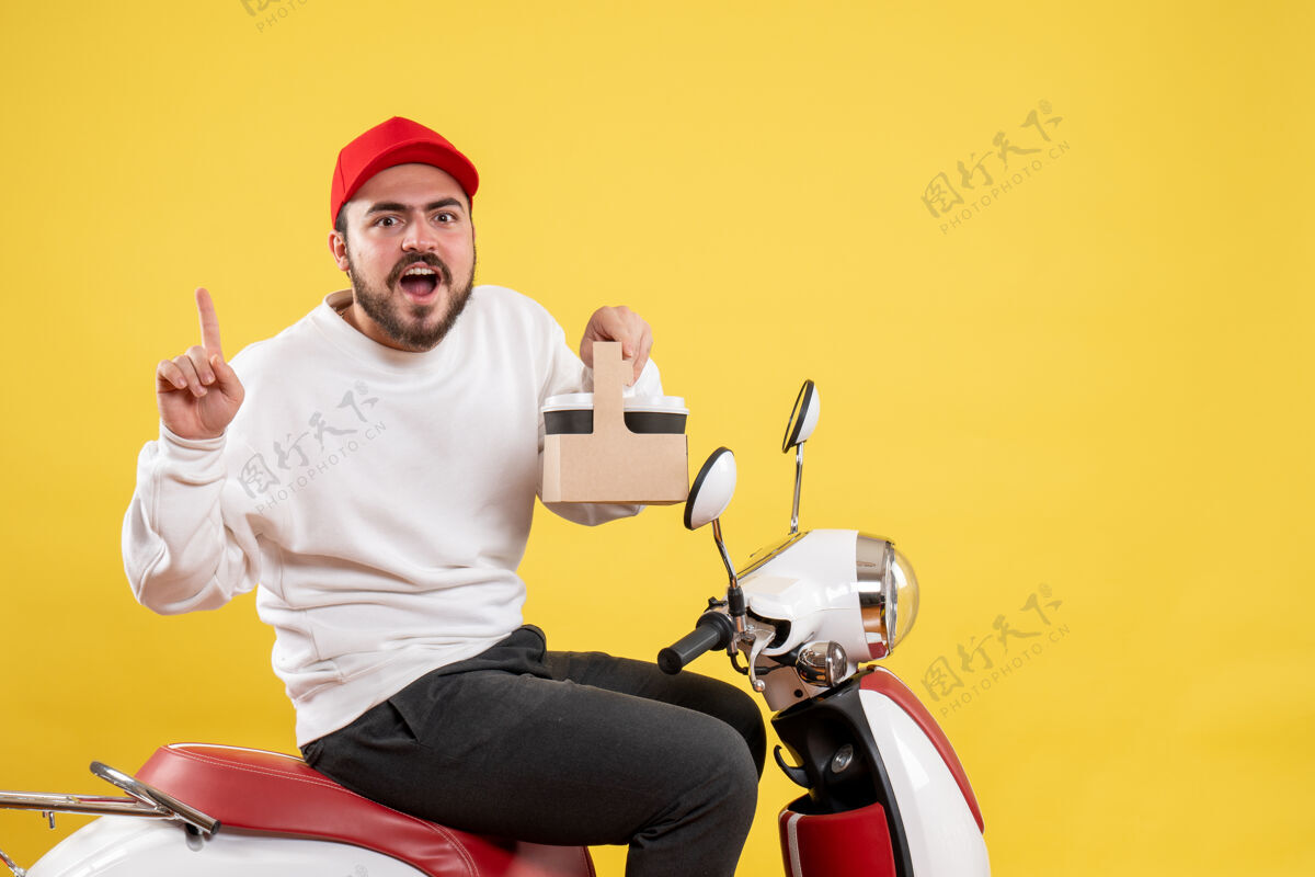 头盔黄色墙上拿着咖啡的男快递员的正视图人自行车前面