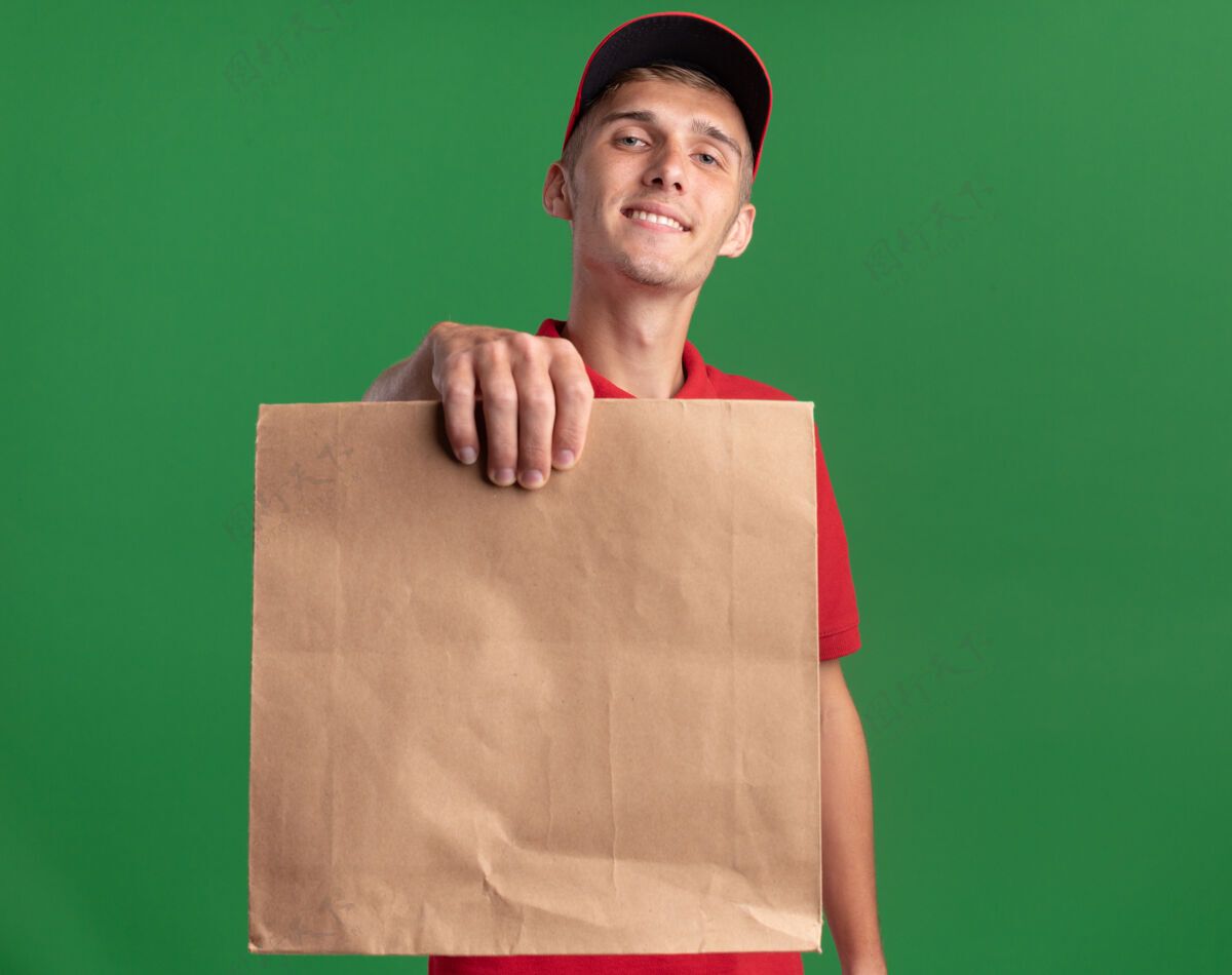 微笑微笑的年轻金发送货男孩拿着绿色的纸包装纸包装金发