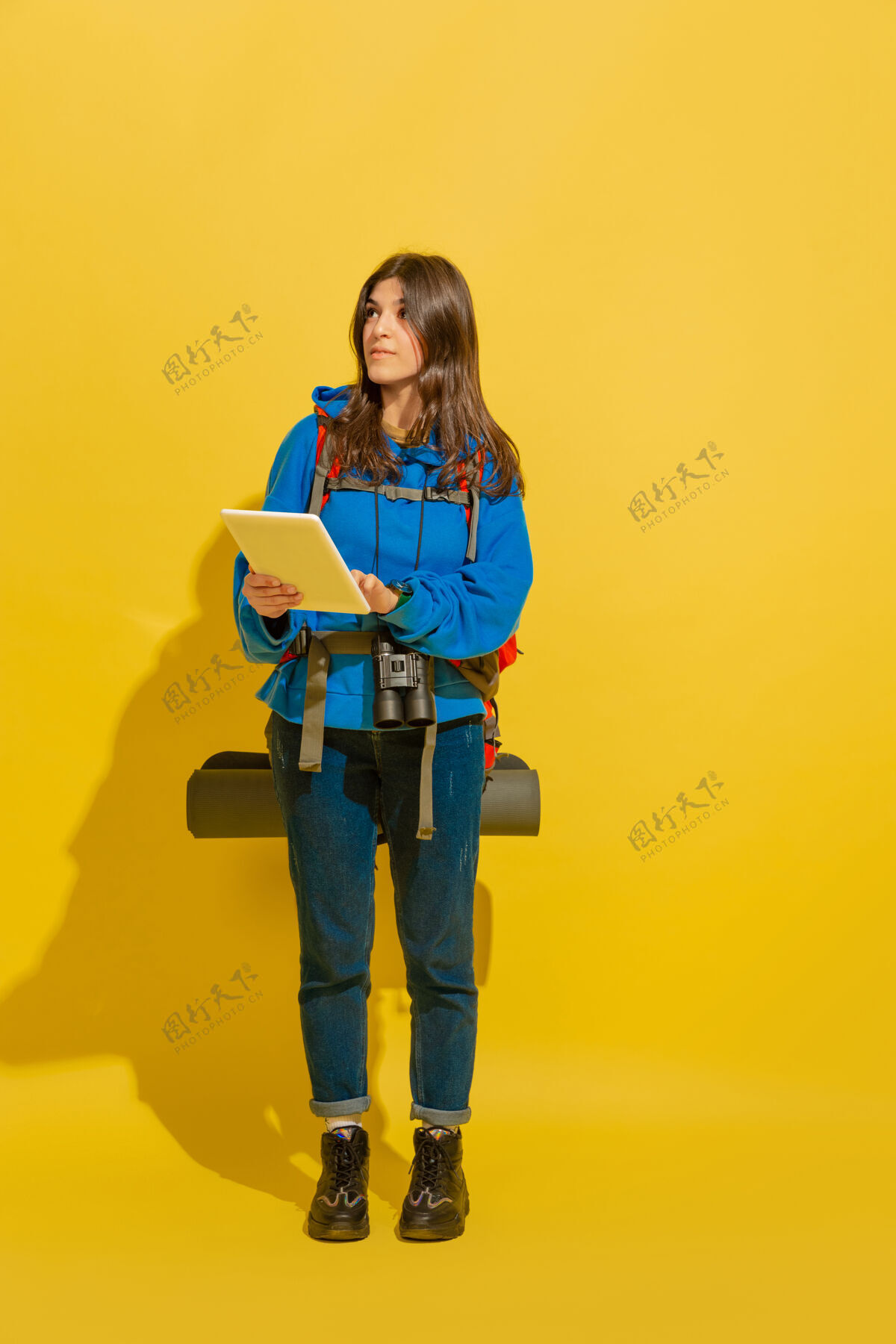 持有用地图找路一个快乐的年轻白人旅游女孩的肖像 带着包和望远镜 隔离在黄色的工作室背景上准备旅游度假胜地 人类的情感 度假长度衣服度假村