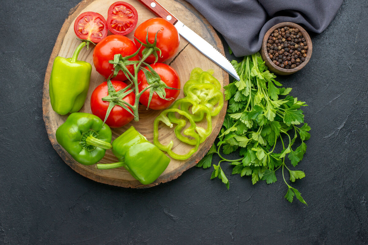 饮食新鲜西红柿和青椒在木板上的俯视图黑色表面上的绿色捆绑沙拉健康捆绑