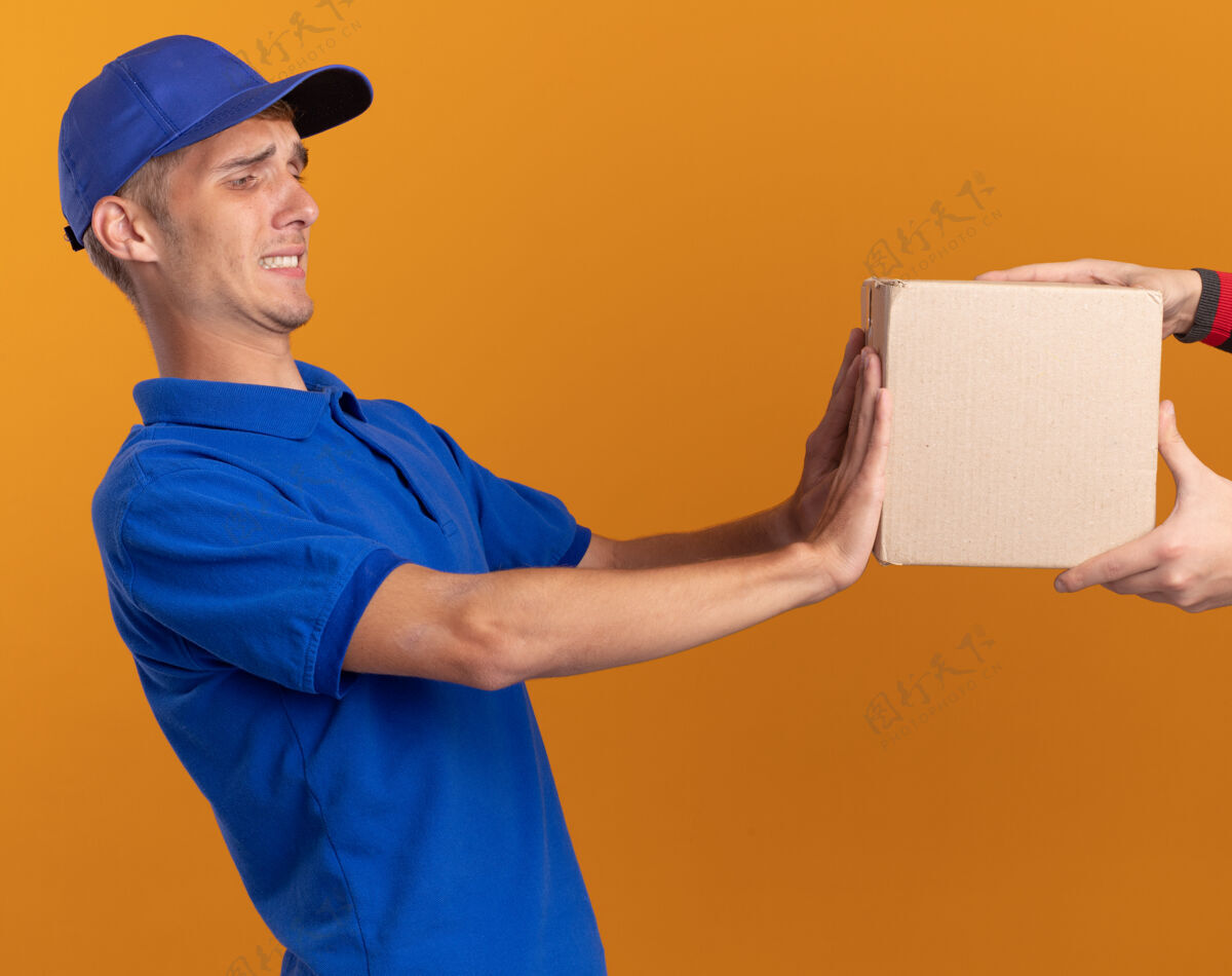 男孩有人把cardbox交给了一个没有出租的年轻金发送货员 他把cardbox推回到了橘色上橙色有人背部