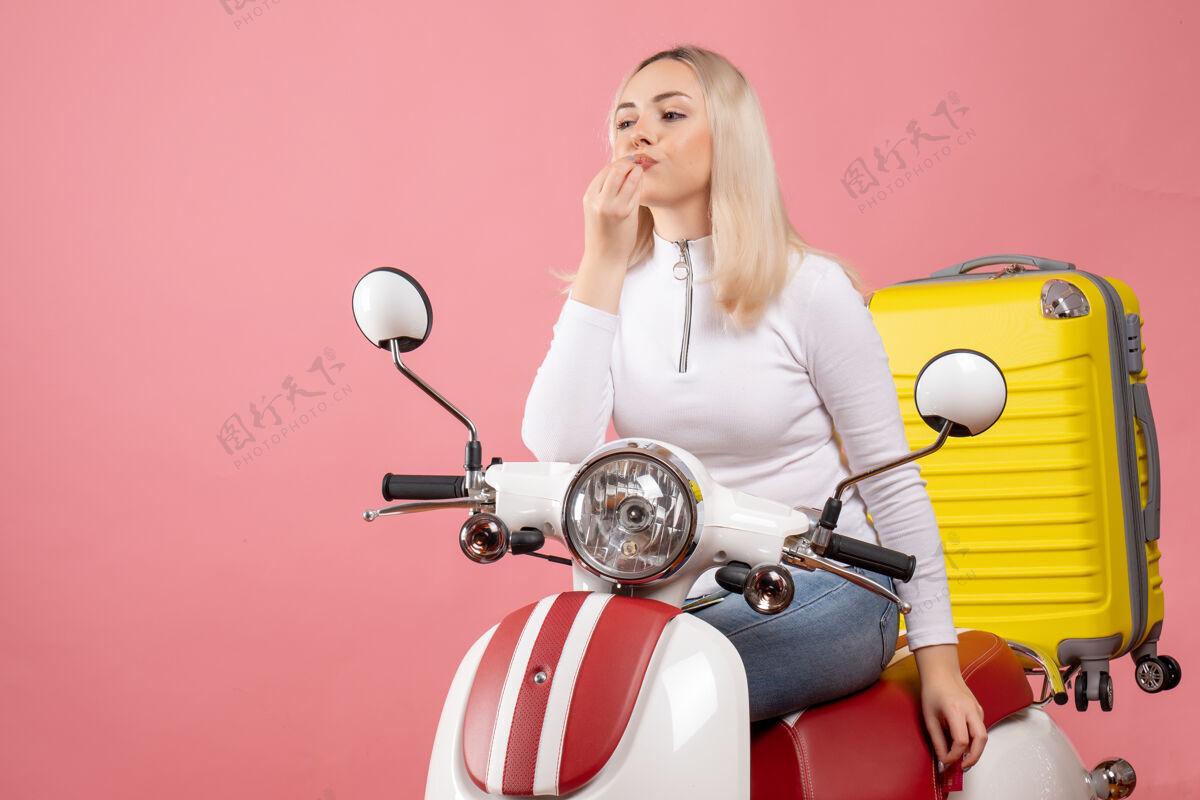 肖像正前方 坐在轻便摩托车上的年轻女士正在做美味的招牌摩托车快乐微笑