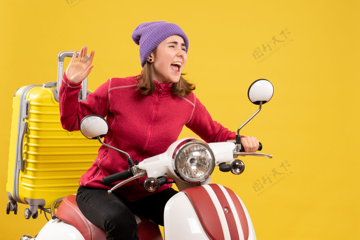 成人前视图：坐在轻便摩托车上挥手的年轻女孩轻便摩托车训练前面