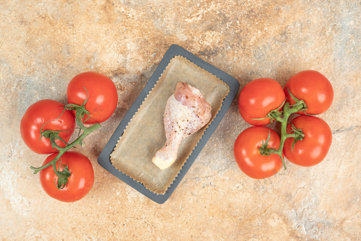 番茄一个深色的平底锅 上面放着西红柿和鸡腿高质量的照片未经料理的可口配料