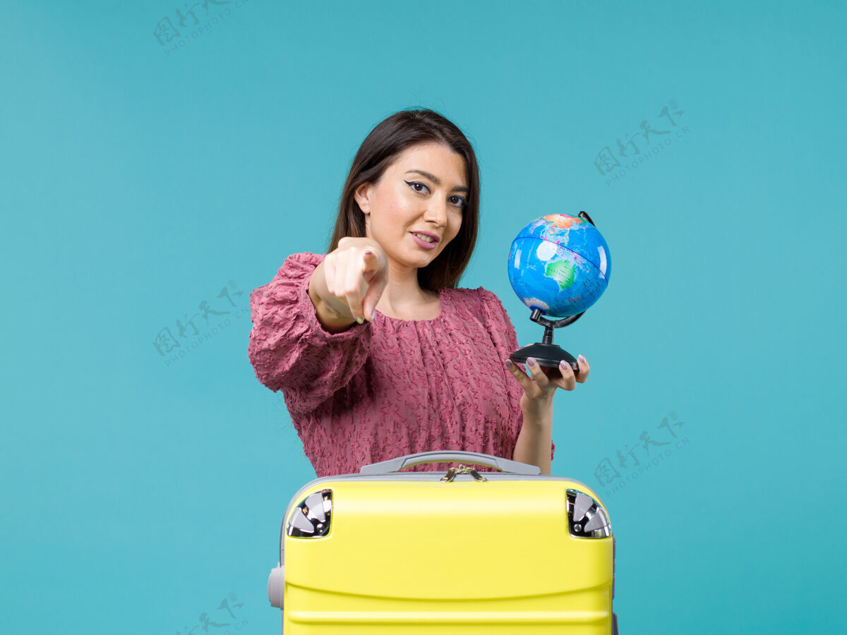蓝色前视女在度假抱着小地球仪在蓝色的背景下旅行海女旅行暑假前面小球