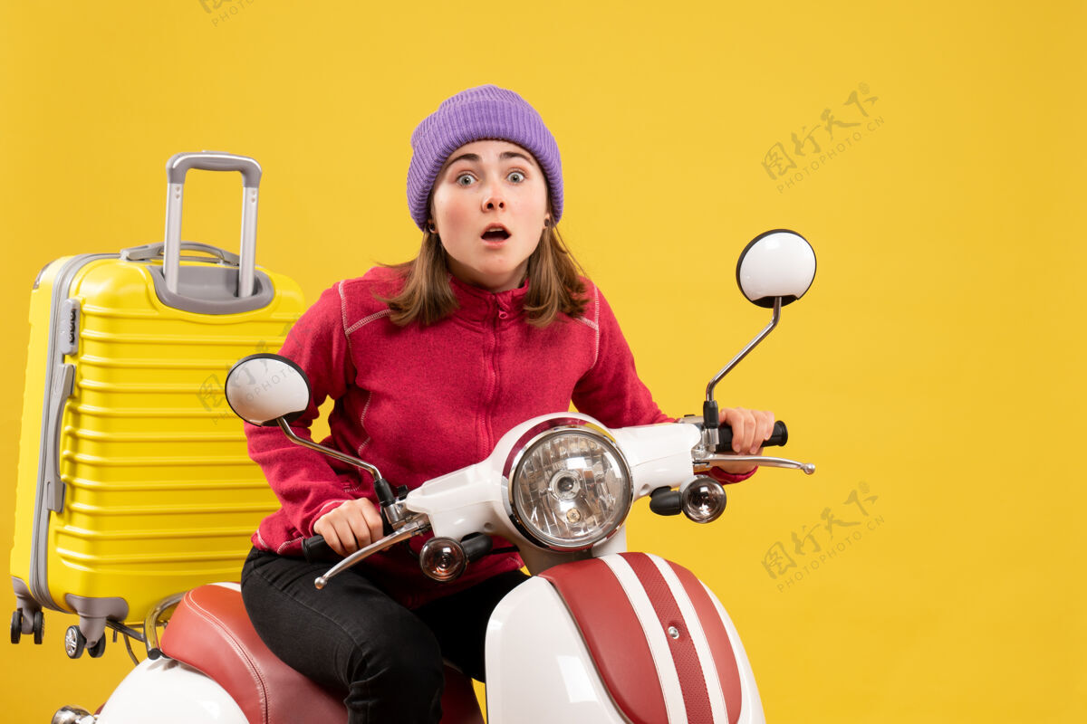 轻便摩托车前视图惊呆了坐在轻便摩托车上的年轻女孩看着前面摩托车人坐着