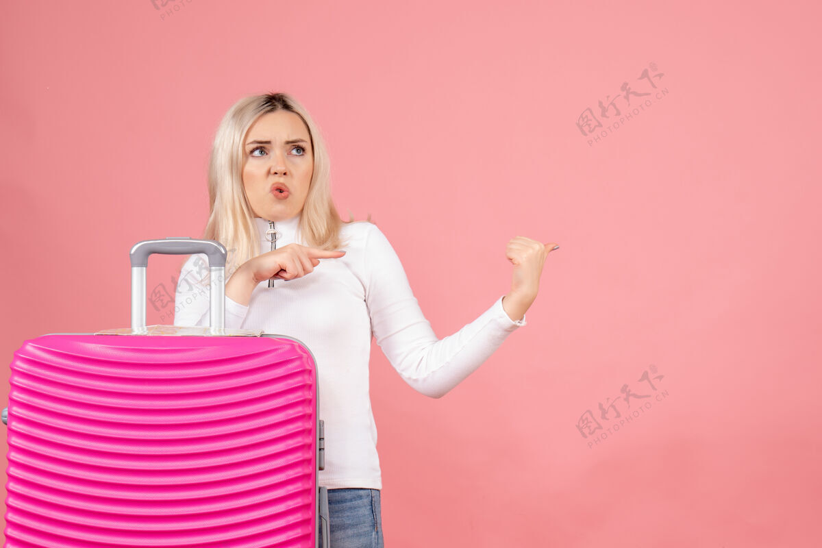 女人正面图是一位漂亮的女士 她拿着粉色的手提箱指着什么东西快乐前面人