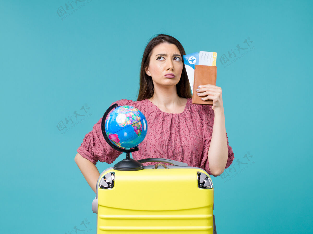 女人正面图度假中的女性拿着她的钱包和机票在蓝色背景海上旅行度假女性旅行人假期视图