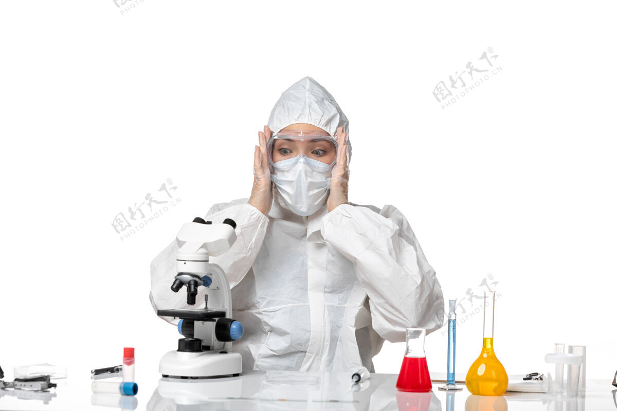 大流行正面图女医生穿着防护服戴着口罩由于害怕用显微镜观察白色背景病毒大流行溅起的covid-专业视野药品