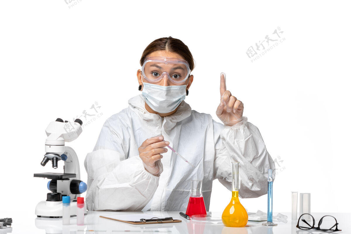 实验室外套前视图穿着防护服 戴着面罩的女医生正在用浅白色背景的冠状病毒大流行病毒冠状病毒溶液工作面罩专业医院