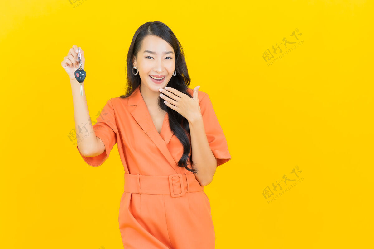 保险肖像美丽的亚洲年轻女子微笑着把车钥匙放在黄色女人亚洲人业主