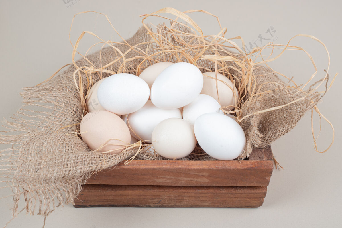 未经料理的新鲜的鸡蛋和干草放在木篮里干草生的家禽